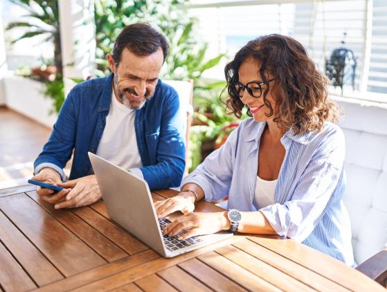 Frau und Mann mittleren Alters sitzen am Tisch und arbeiten mit dem Laptop. Frau und Mann mittleren Alters sitzen am Tisch und arbeiten mit dem Laptop.